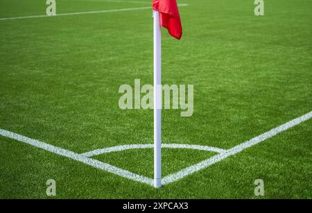 Un vivace campo da calcio verde presenta una bandiera d'angolo alta accanto alle linee bianche appena segnate. Foto Stock