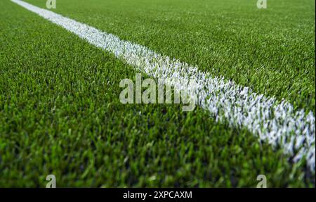 Un vivace campo sportivo verde presenta una linea bianca nitida che segna il confine sotto cieli azzurri. L'erba è lussureggiante e ben tenuta, indicatina Foto Stock