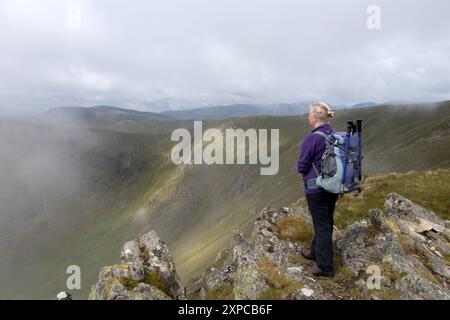 Walker si gode la vista sulla testa di Riggindale dalla cima di Kidsty Pike mentre la nebbia la circonda, Lake District, Cumbria, Regno Unito Foto Stock