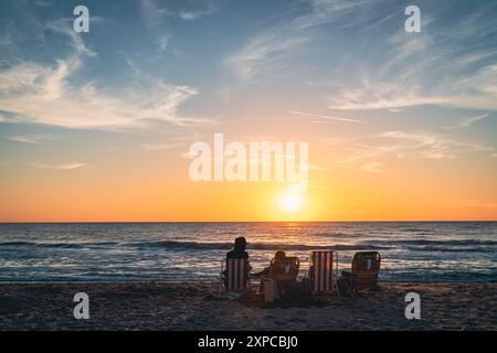 La famiglia а sta guardando il tramonto su una spiaggia di Venice, Florida Foto Stock