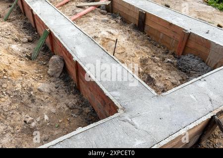 Fondamento di cemento appena posato in cassaforma di legno. La costruzione di case rurali è in corso Foto Stock