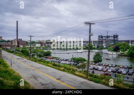 Il parcheggio e la strada sul lungomare del fiume Cuyahoga a Cleveland, Ohio, USA, con il ponte autostradale a ponte verticale Carter Road Bridge Foto Stock