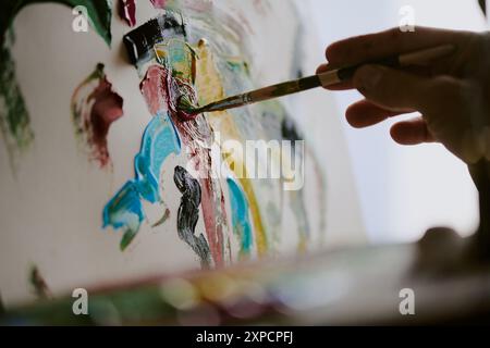Primo piano della mano di un artista maschile irriconoscibile che tiene il pennello su tela, copia spazio Foto Stock