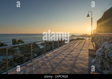 Il lungomare di Castiglioncello al tramonto e una barca in mare. Provincia di Livorno, regione Toscana, Italia Foto Stock