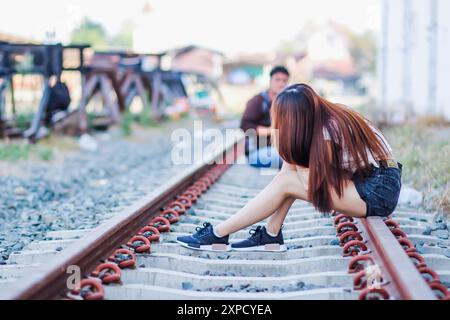 Soft and Smooth Focus, Una giovane donna asiatica cammina da sola lungo i binari della ferrovia verso la sua destinazione desiderata. La parte posteriore di una giovane donna che cammina Foto Stock