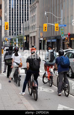 I ciclisti aspettano un semaforo verde per attraversare University ave nel centro di TORONTO, CANADA Foto Stock