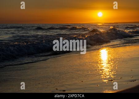 Puesta de sol en la playa de Son Bou, un horizonte dorado con el sol poniéndose sobre el mar. Minorca, España Foto Stock