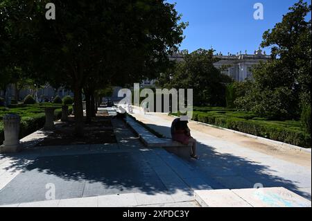 Persone che si rifugiano sotto gli alberi in Plaza de Oriente, di fronte alla piazza reale, nel pomeriggio a seguito delle temperature calde a Madrid in Spagna. Foto Stock