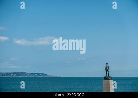 Una statua di Roger Casement sul molo di Dun Laoghaire si affaccia sul mare irlandese con una vista di Howth sullo sfondo. Scultore Mark Richards. Foto Stock