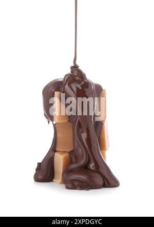 Versare del delizioso cioccolato fuso su caramelle isolate su bianco Foto Stock