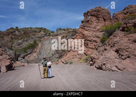 Uomo e moglie si trovano in mezzo alla strada sterrata che conduce attraverso il San Lorenzo Canyon nel New Mexico. L'uomo ha bastone da passeggio e macchina fotografica. Foto Stock