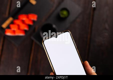 Mani che scattano foto del cibo sushi giapponese con lo smartphone. Spazio per la copia e spazio vuoto per la pubblicità Foto Stock