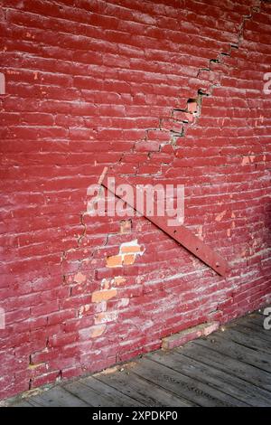 Riparazione di tavole di legno su pareti di mattoni incrinati in un edificio secolare Foto Stock