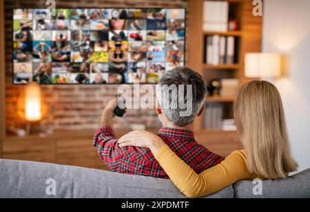 Coppia rilassante sul divano guardando la TV con il telecomando Foto Stock