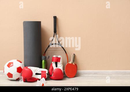 Diverse attrezzature sportive sul pavimento vicino alla parete beige Foto Stock