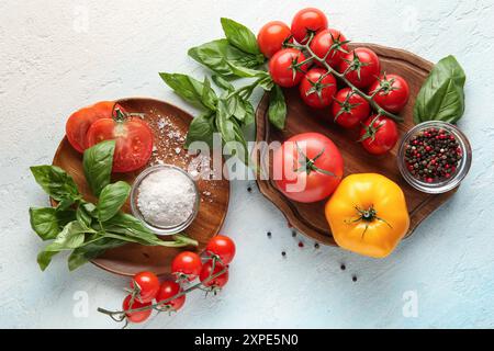 Pomodori a bordo con sale, pepe e rametto di basilico su sfondo azzurro. Vista dall'alto Foto Stock