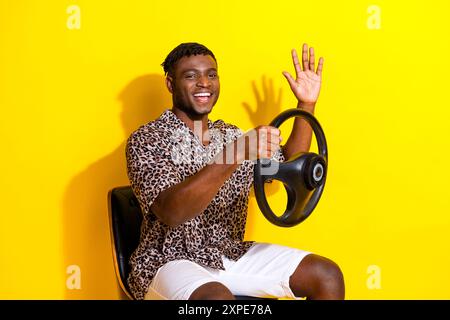 Foto di buon umore conducente sicuro di indossare abiti alla moda guidare la propria auto isolata su uno sfondo giallo brillante Foto Stock