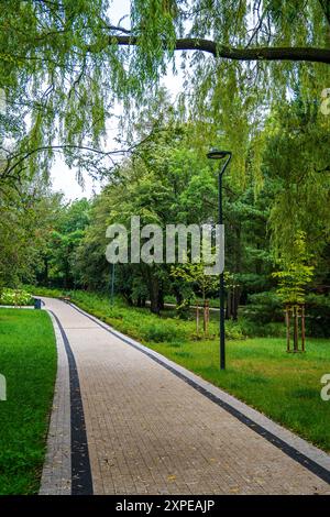 Tranquillo sentiero alberato nel lussureggiante Green Park in un pomeriggio nuvoloso Foto Stock