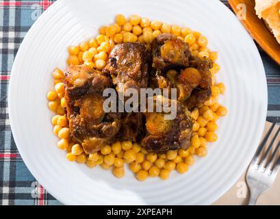 Brasati oxtails con ceci su una piastra bianca Foto Stock