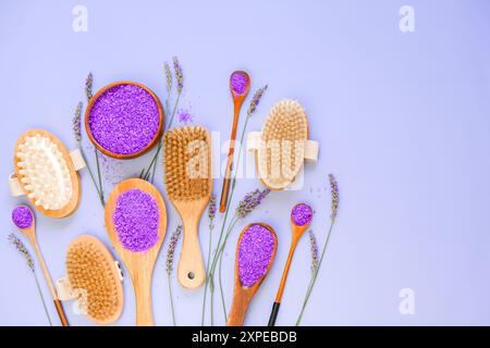 Estratto di lavanda in cosmetici. Sale di lavanda, pennelli a setole naturali e fiori di lavanda sono disposti in modo ordinato su uno sfondo viola. Centro benessere cosmetico Foto Stock