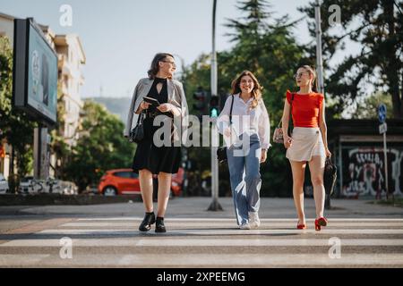 Tre eleganti donne d'affari attraversano la strada della città di giorno Foto Stock