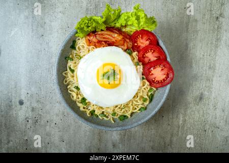 Una ciotola di spaghetti istantanei con uova, pomodori e lattuga Foto Stock