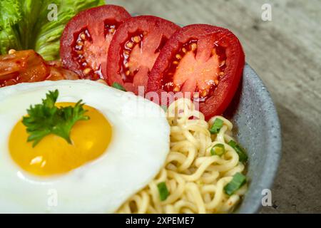 Una ciotola di spaghetti istantanei con uova, pomodori e lattuga Foto Stock