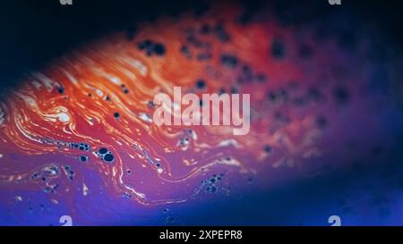 Schiuma color sfocatura. Liquido per bolle d'aria. Le gocce di arcobaleno blu-arancio sfocate fondono l'onda delle fuoriuscite su sfondo nero scuro astratto. Foto Stock
