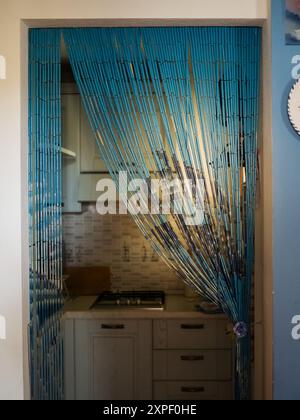 Sbircia attraverso la tenda di bambù Blu: Una cucina accogliente in un noleggio sardo, Olbia Marittima, Italia Foto Stock