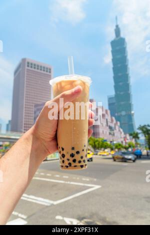 Vista ravvicinata del tè al latte taiwanese con la mano di un uomo Foto Stock