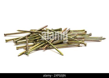 Pila di chiodi in metallo dorato e affilati sparsi su sfondo bianco, primo piano macro Foto Stock