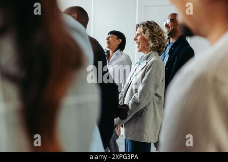 I professionisti che ridono e si godono un momento di luce durante un evento congressuale, favorendo un'atmosfera positiva e coinvolgente. Foto Stock