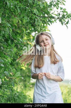 Un bambino con le cuffie che ascolta musica e balla nel parco. Foto Stock