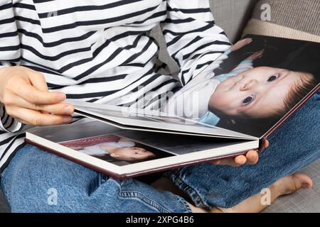 Una donna guarda un libro fotografico sul suo bambino Foto Stock