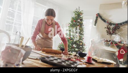 Ritratto della donna che prepara l'impasto per preparare il pan di zenzero per Natale a casa. Allegra casalinga e mamma che preparano dolci da condividere con la famiglia e gli amici per le vacanze Foto Stock
