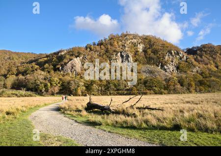 Camminate sul sentiero sotto la collina rocciosa ricoperta di alberi all'estremità sud della passeggiata circolare di Derwentwater in una soleggiata giornata autunnale, Lake District, Cumbria, Inghilterra, Regno Unito Foto Stock