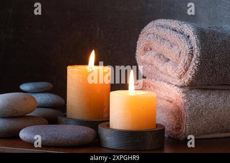 Spa STILL Life con candele, asciugamani e ciottoli su sfondo scuro Foto Stock