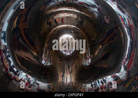 Le persone si riflettono all'interno della scultura Cloud Gate, nota anche come Bean, la superficie luminosa e riflettente della scultura distorce l'immagine del pe Foto Stock
