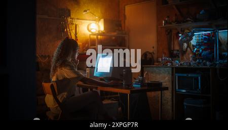 Web Designer donna ispanica che utilizza un vecchio computer desktop in retro Garage Late at Night. Specialized Internet Enthusiast Writing Code at Home. Programmazione di un sito Web di social network di successo negli anni novanta. Foto Stock