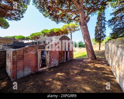 Edifici funerari di una o due piani quadrati, spesso circondati da un recinto; soffitti a botte o tetti piatti; facciate in mattoni adornate con timpani triangolari, plinti, lesbiche, colonne e capitelli; piccole finestre e porte incorniciate da soglie in travertino, stipiti ed epistoli. La necropoli si sviluppò ai lati della via Flavia tra la fine del i e il IV secolo d.C. - Necropoli di Portus nell'Isola Sacra, Fiumicino, Roma, Italia Foto Stock