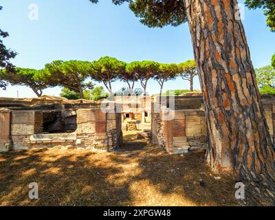 Edifici funerari di una o due piani quadrati, spesso circondati da un recinto; soffitti a botte o tetti piatti; facciate in mattoni adornate con timpani triangolari, plinti, lesbiche, colonne e capitelli; piccole finestre e porte incorniciate da soglie in travertino, stipiti ed epistoli. La necropoli si sviluppò ai lati della via Flavia tra la fine del i e il IV secolo d.C. - Necropoli di Portus nell'Isola Sacra, Fiumicino, Roma, Italia Foto Stock