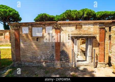 Edifici funerari di una o due piani quadrati, spesso circondati da un recinto; soffitti a botte o tetti piatti; facciate in mattoni adornate con timpani triangolari, plinti, lesbiche, colonne e capitelli; piccole finestre e porte incorniciate da soglie in travertino, stipiti ed epistoli. La necropoli si sviluppò ai lati della via Flavia tra la fine del i e il IV secolo d.C. - Necropoli di Portus nell'Isola Sacra, Fiumicino, Roma, Italia Foto Stock