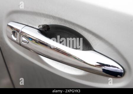 Primo piano del pomello della maniglia della portiera dell'auto con graffi sulla superficie verniciata causati dal contatto delle dita durante l'apertura della portiera Foto Stock