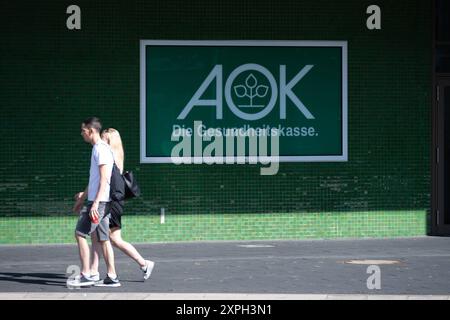 Menschen gehen vor der AOK filiale in Essen am Berliner Platz entlang, AOK-Logo, allgemein, Feature, Randmotiv, Symbolfoto Essen, 06.08.2024. *** Persone che camminano lungo Berliner Platz di fronte alla filiale AOK di Essen, logo AOK, generale, caratteristica, motivo di confine, foto simbolica Essen, 06 08 2024 Foto Stock