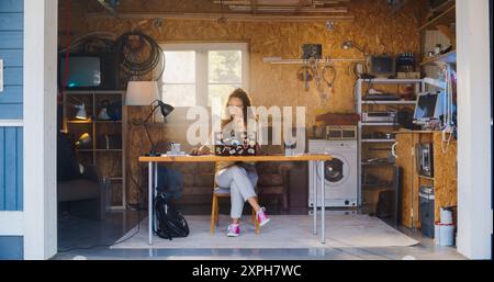 Sviluppatore di software femminile ispanico che codifica su computer portatile nel Garage at Home. Giovane donna concentrata che lavora su innovative Online Service Startup Company. Imprenditore digitale che avvia il concetto di business Foto Stock