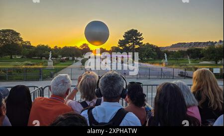 Quando il sole tramonta su Parigi, molti curiosi vengono a radunarsi intorno ai Giardini delle Tuileries per guardare il Calderone olimpico del 2024 prendere il volo Foto Stock