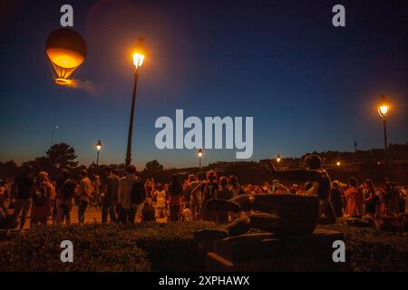 Quando il sole tramonta su Parigi, molti curiosi vengono a radunarsi intorno ai Giardini delle Tuileries per guardare il Calderone olimpico del 2024 prendere il volo Foto Stock