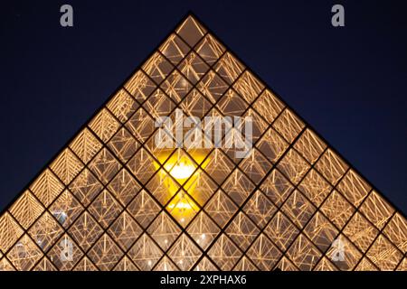 Quando il sole tramonta su Parigi, molte persone curiose vengono a riunirsi al Louvre con la Piramide per vedere il Caldrone Olimpico del 2024 Foto Stock