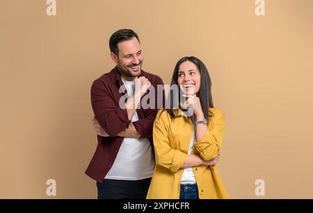 Giovane romantico che guarda una bella ragazza sorridente con la mano sul mento. Coppia felice e attraente vestita con abiti casual in posa allegramente mentre sei in piedi Foto Stock
