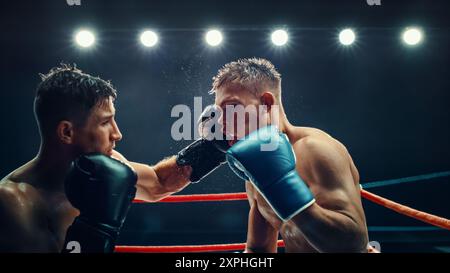 Intenso match di pugilato tra due male Fighters sotto Bright Lights, potenti pugni e feroce competizione sul ring. Sudore e determinazione in questo momento sportivo ad alta energia. Foto Stock